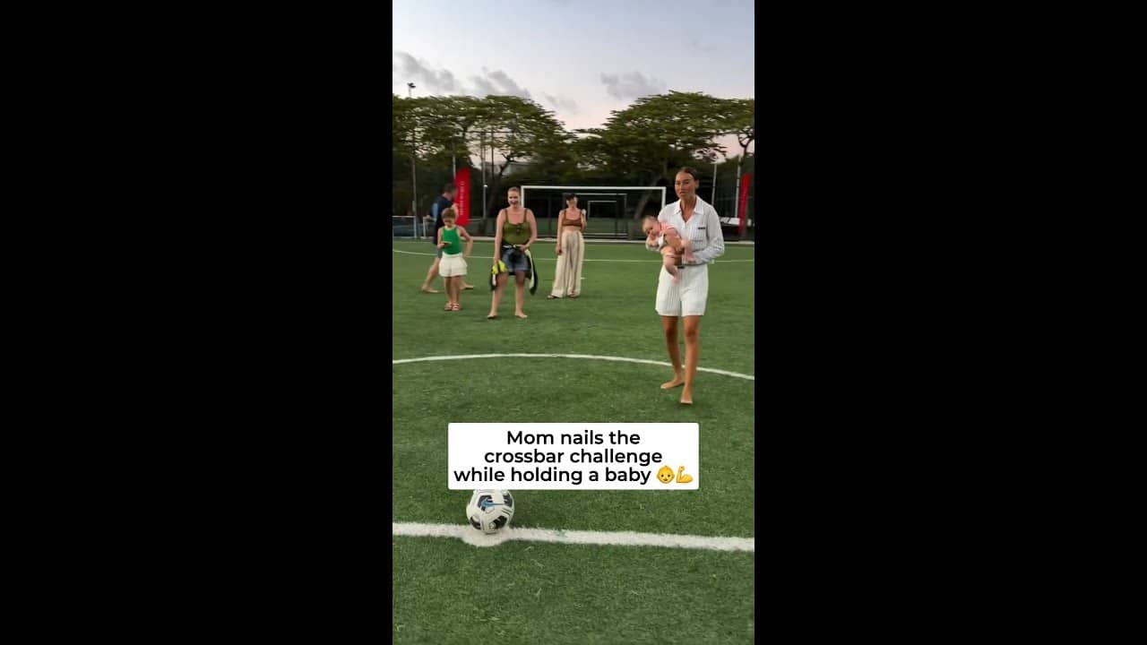 Mom nails the crossbar challenge while holding a baby.