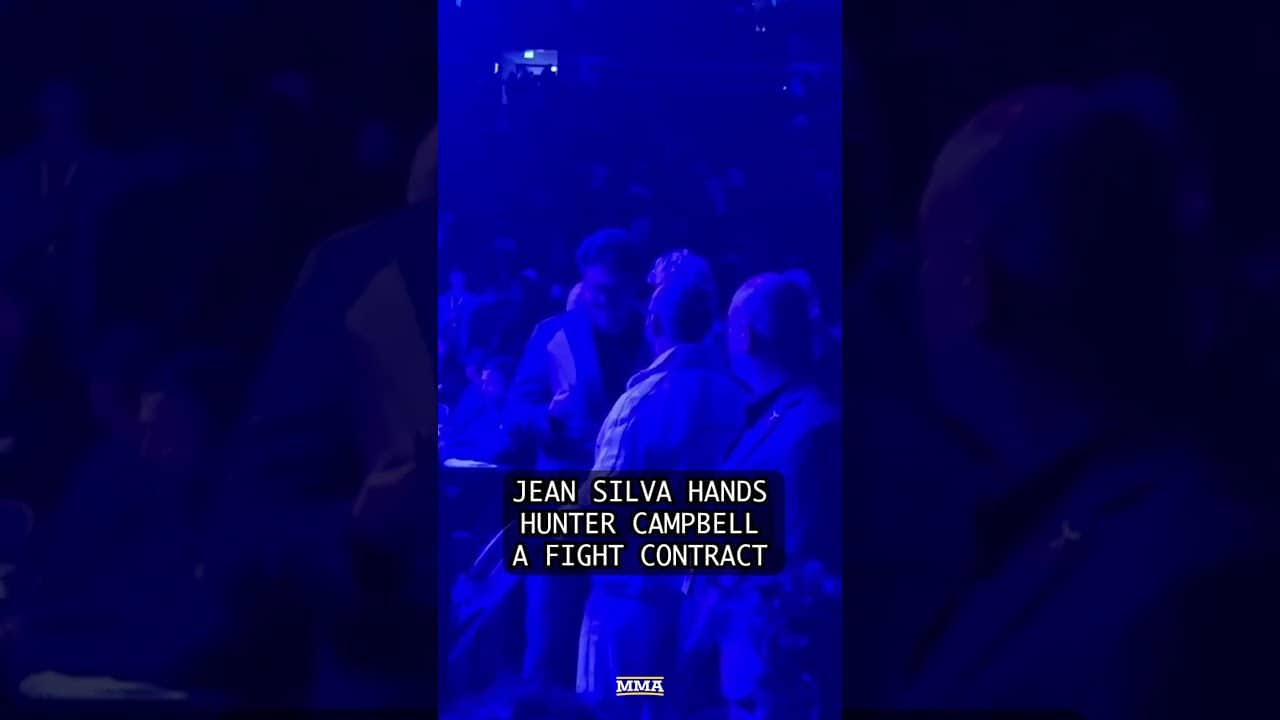 Jean SIlva hands Hunter Campbell a contract to fight champion Alex Volkavnoski